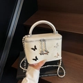 Cream white crossbody bag with metal bow accents and circular top handle design - Off-white