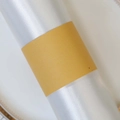 Macro shot of glossy white satin napkins with golden paper bands for table decor - Gold