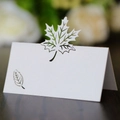 Detail showing laser-cut maple leaf place card with pearlescent finish on wood surface - White
