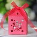 Gros plan d'une boîte à bonbons rose ajourée de flocons avec un ruban décoratif - Rouge Perlé