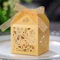 Détail d'une boîte à bonbons dorée à roses évidées avec un nœud en ruban sur une assiette - Or