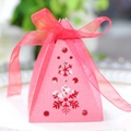 Macro shot of pink pyramid gift box with snowflake cutout and red ribbon bow detail - Pearlescent Red