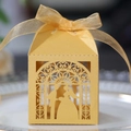 Close-up of golden laser-cut wedding candy box with bride and groom silhouette and ribbon - Gold