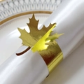 Detailansicht eines goldenen Ahornblatt-Serviettenrings mit polierter Oberfläche auf Tuch - Reflektierendes Goldgelb