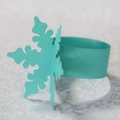 Macro detail of mint green laser-cut snowflake paper napkin ring with pearlescent finish - Teal Blue