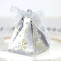 Close-up of silver pyramid candy box with snowflake cutout patterns and a silk ribbon bow - Reflective Silver