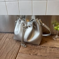 Detail of silver metallic leather bucket bag with chain drawstring on wooden surface - Silver