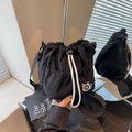 Black nylon drawstring bucket bag with cat embroidery and adjustable strap in a lifestyle setting - Black