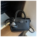 Detail view of black lychee grain mini bag with heart charms and buckle strap on wood - Black