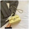 Detail of quilted yellow handbag featuring floral scarf handle and silver bottom studs - Yellow