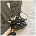 Detail of black quilted leather handbag featuring silver clasp, chain, and silk scarf handle - Black