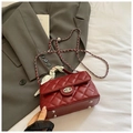 Detail of burgundy quilted handbag with silver twist lock and scarf-wrapped handle - Red