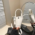 White bucket bag with lychee texture and slender top handle shown in mirror reflection - White