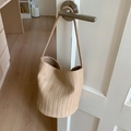 Detail shot of the V-shape woven texture and sturdy round base of a beige bucket bag - Khaki