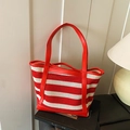 Red and white striped tote bag with red handles in a cozy home setting - Red