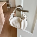 Detail of ruched cream leather bag with knot handle hanging on a door handle - White