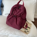 Minimalist burgundy drawstring backpack with textured nylon fabric on white bedding - Red