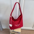 Dettaglio della borsa tote in tela rossa con scritte bianche e piccola borsa appesa - Rosso