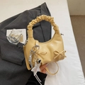 Detail van gele geplooide tas met strik en zilveren ster- en hartvormige hangers - Geel
