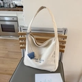 Borsa tote minimalista in tela beige con stampa di lettere e ciondolo blu su sedia - Bianco Sporco