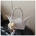 Close-up of a stylish light grey bucket bag with dual handles and a cute plush dog pendant - With Charm / Purple