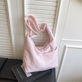 Pink nylon tote bag with textured ruffles and shoulder strap on a book background - Pink