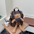 Deep brown backpack with printed bear pattern and cute plush charm on a wooden table - Coffee with Pendant