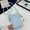 Detalle del bolso bandolera azul claro en cuero granulado con colgante de haba plata - Azul