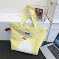 Yellow canvas tote bag featuring a large white duck print and blue brand tag - Yellow