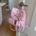 Detail of light pink mini backpack featuring a decorative bow and textured faux leather - Pink