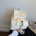 Detail view of cream white textured leather backpack with ribbon drawstring and front pockets - White