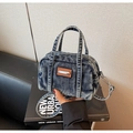 Close-up detail of denim texture and brown leather patch on blue mini boston bag - Denim Blue