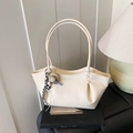 Chic cream-white tote bag with lychee texture and decorative tassel on a striped wall - With Charm / Off White
