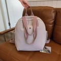 Wasserdichter lila Nylon Rucksack mit rosa Riemen und Metall-Logo auf Ledersofa - Rosa