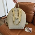 Hellbeiger wasserdichter Nylon-Rucksack mit Griff und Metall-Logo auf Ledersofa - Khaki