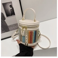 Detail der bunten geflochtenen Zylindertasche mit cremefarbenem Leder und Goldakzenten - Weiß