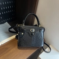 Retro black box handbag with adjustable shoulder strap on a wooden tabletop display - Black