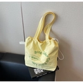 Light yellow drawstring canvas tote bag with green artistic print and shoulder straps - Yellow