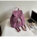 Close-up of purple plaid canvas backpack with drawstring and white buckle on white surface - Purple