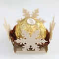 Macro shot of Ferrero Rocher in a laser-cut white snowflake decorative candy box holder - Jewelry Cream Star