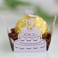 Close-up of laser-cut wedding cake paper holder with golden chocolate on white desk - Light Purple