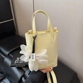 Pale yellow bucket bag with a large white flower charm and adjustable shoulder strap - Yellow