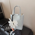 Light blue faux leather bucket bag with a white flower charm and adjustable shoulder strap - Blue
