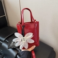 Red glossy bucket bag with large white flower charm and detachable shoulder strap - Red