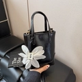 Glossy black mini bucket bag with white floral charm and golden hardware detail - Black