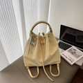 Cream bucket bag with drawstring closure and silver heart charm in a workspace setting - Yellow (With Pendant)