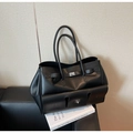 Detail of black leather tote bag with silver buckle on a textured sofa setting - Black