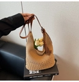 Detail der gewebten Strohtasche mit braunem Lederband, Quaste und Lochmustern - Khaki