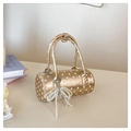 Close-up of golden polka dot cylinder bag with elegant pearl bow charm and metal zipper - Gold With Charm
