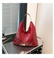 Close-up of red patent leather hobo bag with hexagonal metallic rivets on industrial cart - One Size / Red